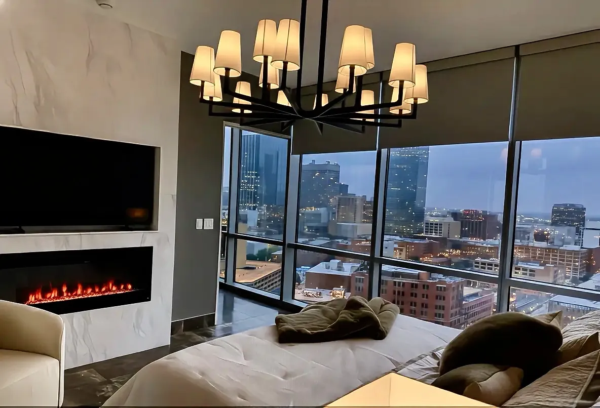Bedroom at night with fireplace and city view